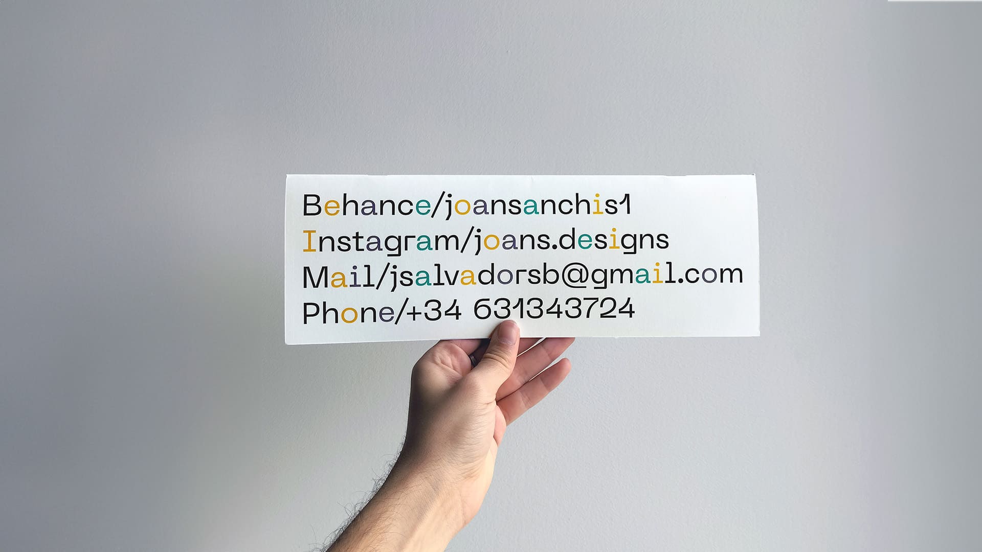 Mano sosteniendo la contraportada de un planificador, mostrando la información de contacto de Joan Sanchis (Behance, Instagram, Mail, Phone)